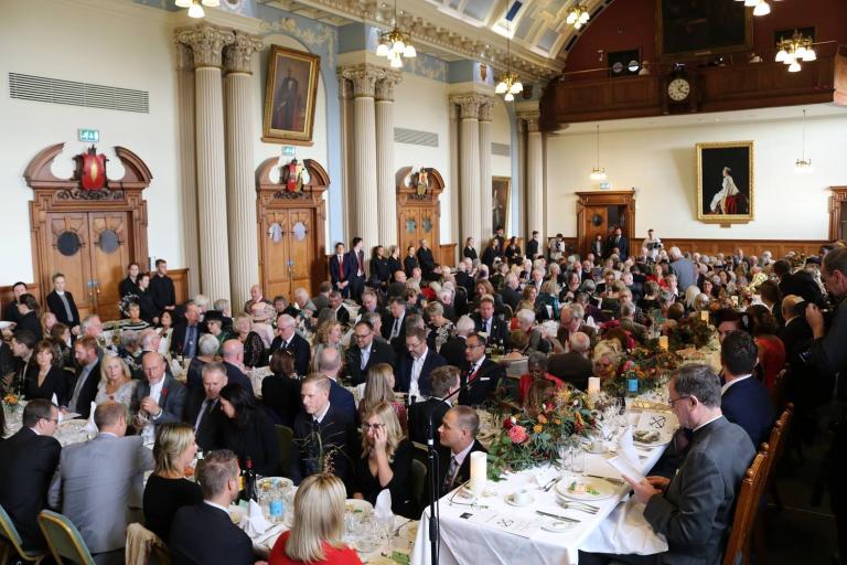 A photo of a large group of people sitting at tables in Colchester City Hall's Moot Hall for the oyster festival