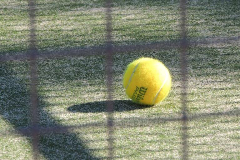 Photo of a tennis ball on the ground of a court