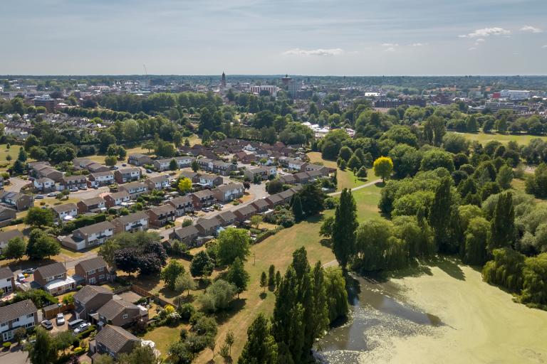 Aerial view of Colchester City with Town Hall and Jumbo in the background. A residential area can also be seen with green spaces and trees on a sunny day