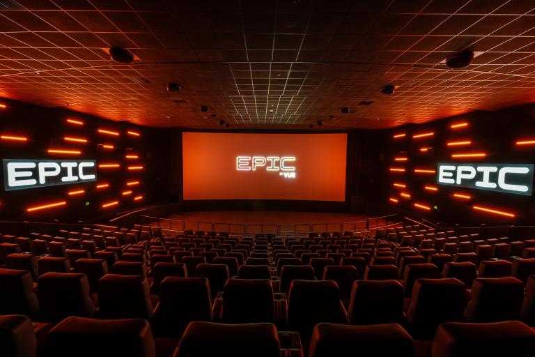 EPIC by Vue cinema auditorium with rows of seats facing a large screen, illuminated by orange lighting.