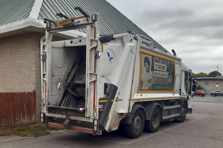 A Colchester City Council waste collection vehicle parked beside a single storey building