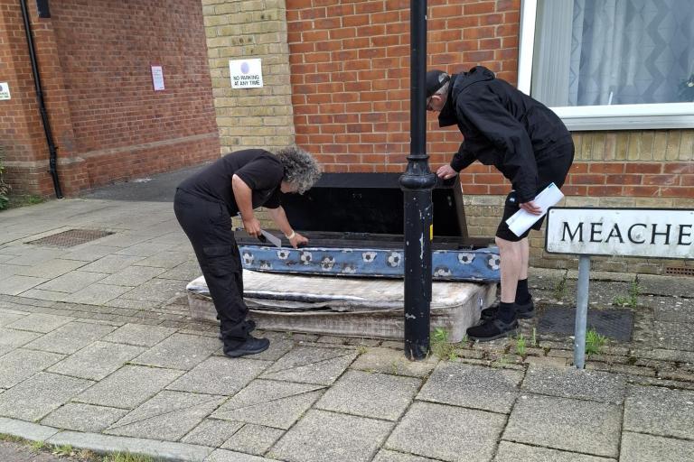 Two people clear up a fly-tip on the pavement at the Hythe