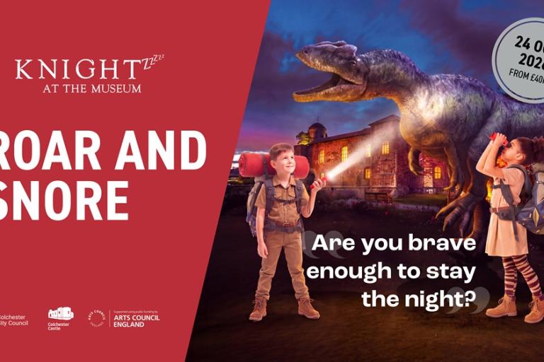 Two people with backpacks and torches stand in front of a dinosaur and museum at night.