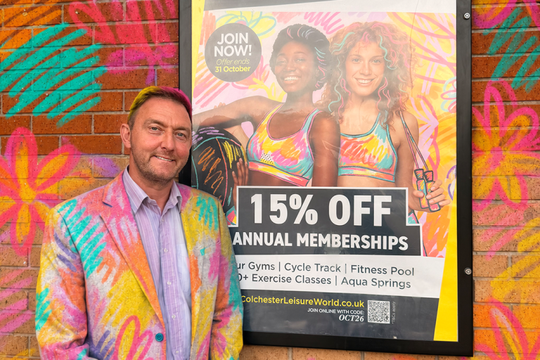 Cllr Martin Goss standing beside a promotional poster for Leisure World
