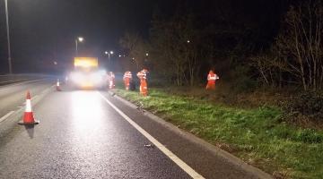 Council team clearing litter from a verge on the A12 at night