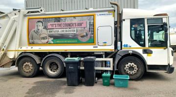 A waste and recycling lorry with wheelie bins and other containers in the foreground
