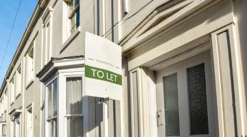 A row of terraced houses with a 'To Let' sign in the foreground