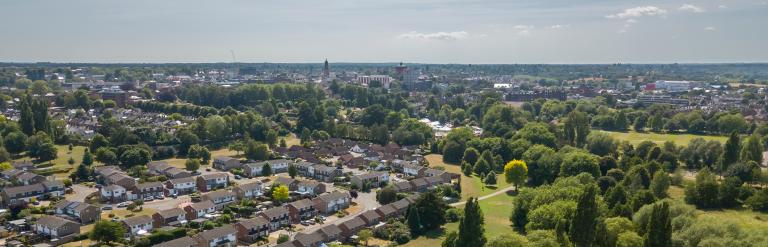 Aerial view of Colchester City with Town Hall and Jumbo in the background. A residential area can also be seen with green spaces and trees on a sunny day