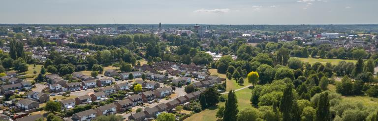 Aerial view of Colchester City with Town Hall and Jumbo in the background. A residential area can also be seen with green spaces and trees on a sunny day