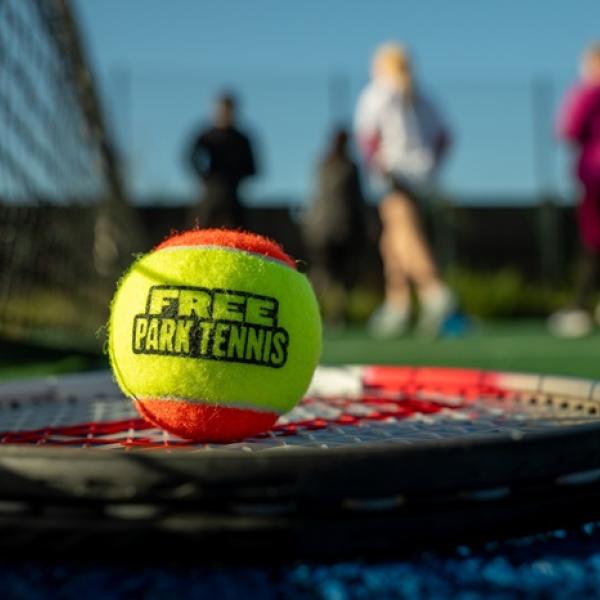 Tennis ball on a racket with the text 'Free Park Tennis' on it