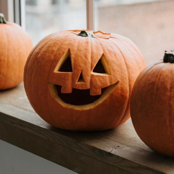 Photo of three pumpkins, the middle one has a face carved into it