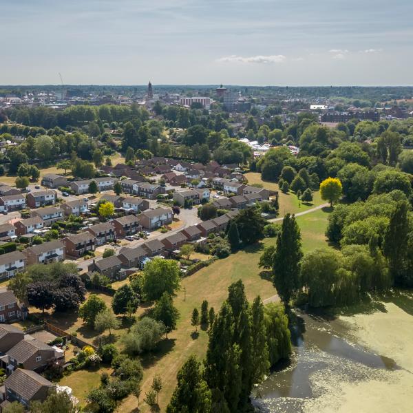Aerial view of Colchester City with Town Hall and Jumbo in the background. A residential area can also be seen with green spaces and trees on a sunny day