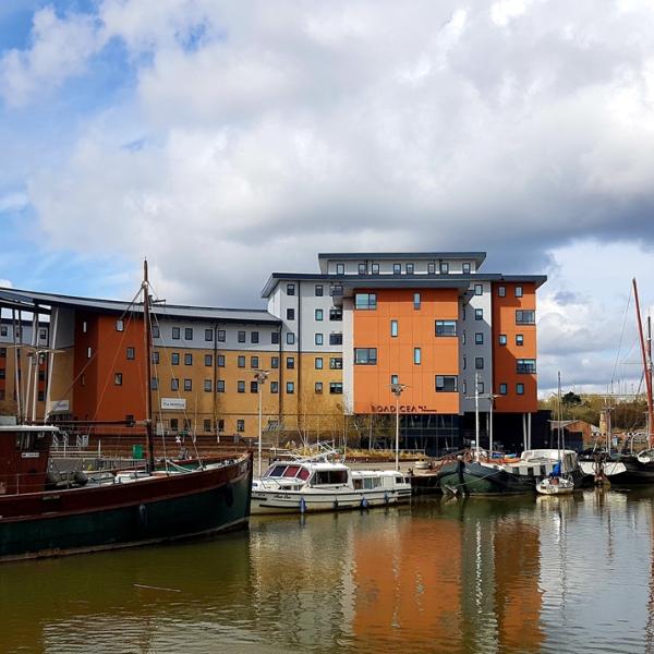 A picture of the river in Hythe Colchester with boats docked and buildings in the background