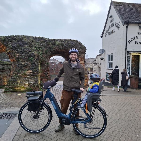 Daniel Stebbings poses with an ebike in front of Balkerne Gate