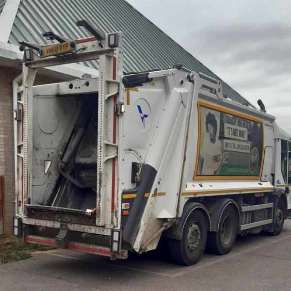 A Colchester City Council waste collection vehicle parked beside a single storey building