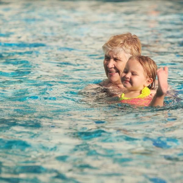 A woman holding a child above the water in a swimming pool