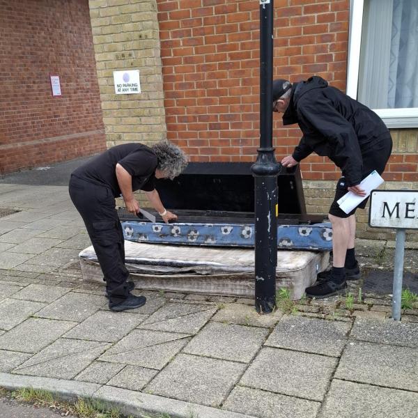 Two people clear up a fly-tip on the pavement at the Hythe